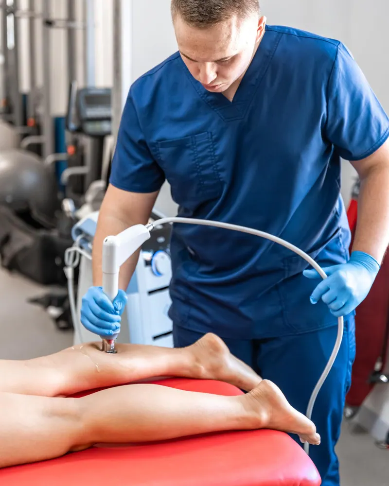 Clinician delivering shockwave treatment to a patient’s foot in a treatment room